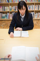 Student reading book in library wearing uniform