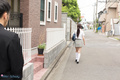 Student walking along street in uniform long hair in ponytail