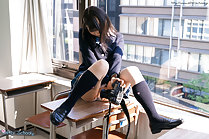 Sitting on desk in uniform knees raised