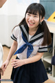 Standing in classroom pigtails falling over her uniform beaming smile