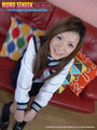Japanese kogal yua ando sitting in uniform on couch hands on her knees.jpg