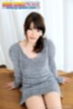 Yuna ishihara sitting on wood flor hands down beside her long hair in ponytail over her shoulder wearing grey sweater