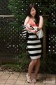 Standing in garden wearing striped dress pulling dress down exposing bra wearing high heels