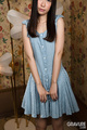 Standing in gingham dress long hair hands at her front