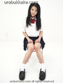 Kogal seated on chair in uniform long hair down to her chest hands on her thighs knees pressed together.jpg